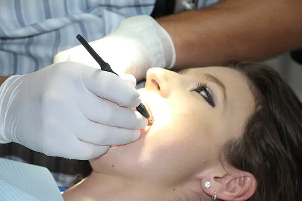 Odontólogo de Clínica Dental O Troncal revisando la boca de una paciente durante una consulta