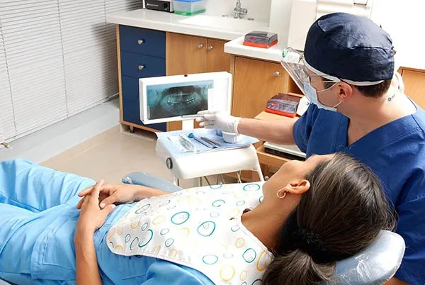 Odontólogo de Clínica Dental O Troncal mostrando una radiografía panorámica a una paciente en el gabinete